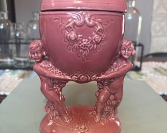 Vaso o urna antica tedesca in ceramica smaltata rosa con coperchio, decorato con cherubini.