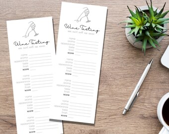 May include: Two white wine tasting sheets with the text "Wine Tasting" and prompts for name, aroma, appearance, taste, finish, and score. A pen, a cup of coffee, a small plant, and a laptop are on a wooden surface.