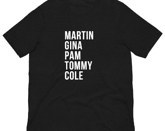 Op de afbeelding: Zwart T-shirt met witte tekst die "MARTIN GINA PAM TOMMY COLE" luidt