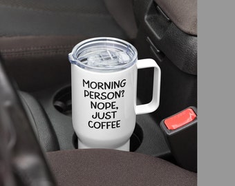 May include: White travel mug with a black inscription that reads "Morning Person? Nope, Just Coffee".