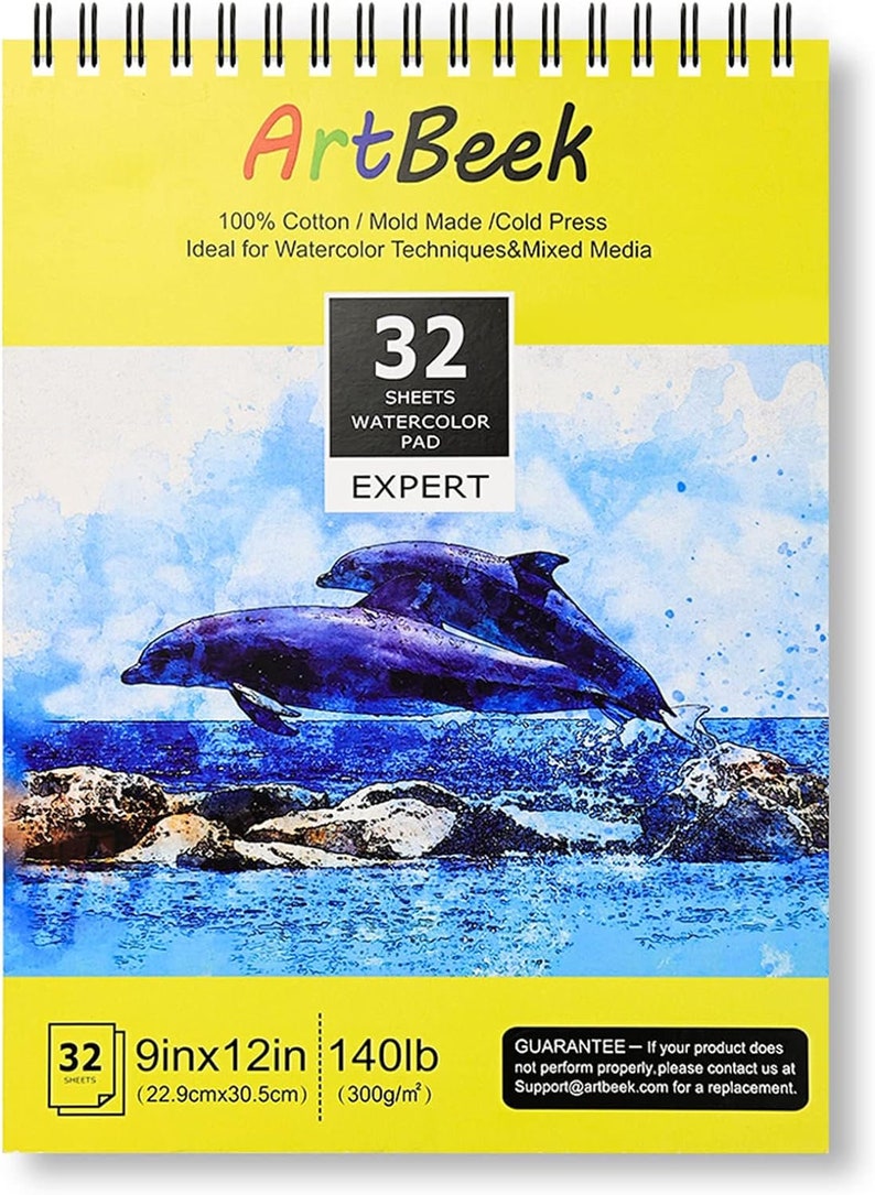 May include: A yellow watercolour pad featuring a dolphin illustration. The pad measures 9 inches by 12 inches and is 140lb (300g/m&sup2;). It is made from 100% cotton and is cold pressed. The pad contains 32 sheets and is labelled "Expert".