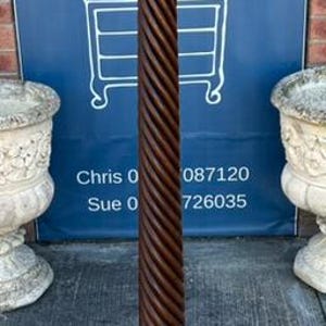 May include: A tall, dark brown wooden pedestal stand featuring a circular top platform, a central column with a prominent spiral-carved design, and a sturdy, tiered circular base. The structure is finished with a smooth, polished wood grain.
