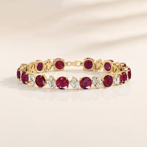 May include: A gold bracelet with oval rubies and baguette-cut diamonds. The bracelet's design alternates ruby and diamond clusters, creating a luxurious look. The clasp is gold. The bracelet is approximately 18 cm in length.
