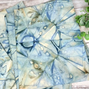 May include: A stack of blue and white patterned fabric squares with a subtle watercolour effect. The fabric has a crinkled texture and appears to be handmade.