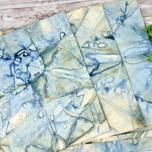May include: A stack of handmade, blue and white marbled paper sheets. The paper has a unique, organic pattern and is perfect for crafting and art projects.