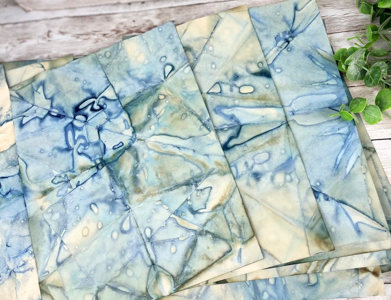 May include: A stack of handmade, blue and white marbled paper sheets. The paper has a unique, organic pattern and is perfect for crafting and art projects.