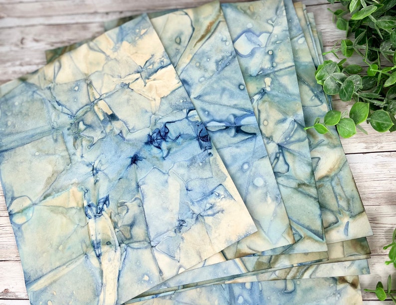 May include: A stack of blue and white marbled paper sheets. The paper has a unique, abstract pattern with shades of blue and white.