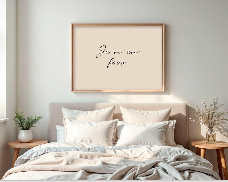 May include: A framed print with the text "Je m'en fous" in a bedroom setting. The print has a light beige background and a wooden frame. The bed is made with white pillows and a light beige comforter. Two small wooden side tables are on either side of the bed.