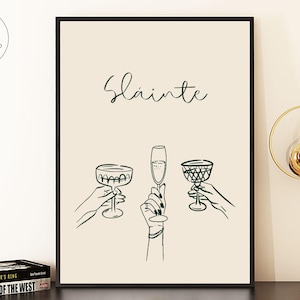 以下が含まれることがあります： 「Slainte」という単語が上に筆記体で書かれた、3つのシャンパングラスが描かれたミニマルなデザインの印刷可能なアートプリントです。