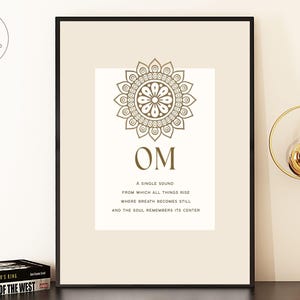 May include: Framed art print featuring the word "OM" in a stylized font, with a decorative mandala above and text below. The print is in a neutral color palette and includes the text "A single sound from which all things rise..."