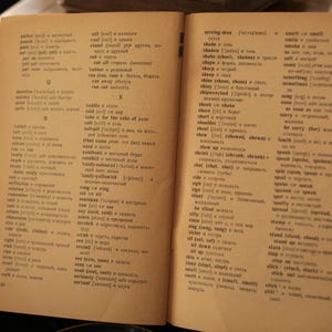May include: An open book with a dictionary of words and their definitions. The book is open to the pages for the words "shade" and "sing".