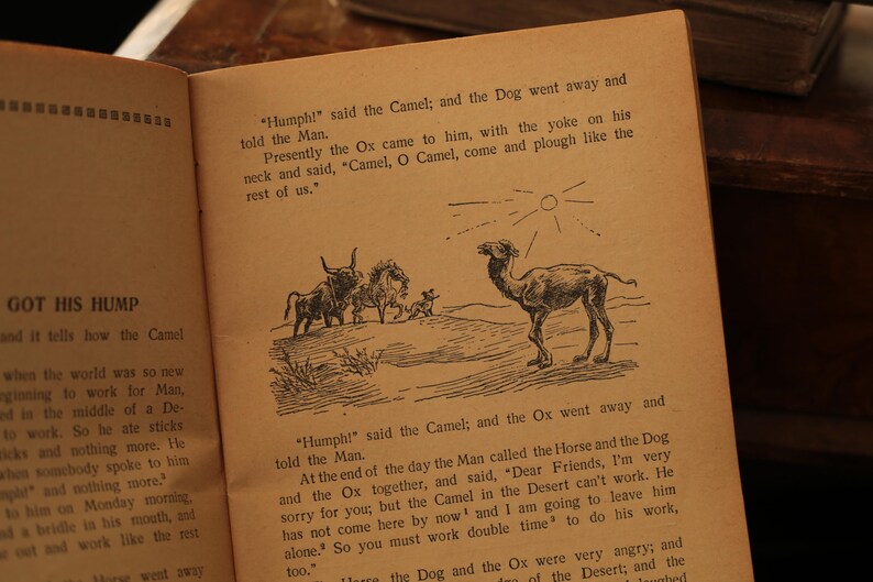 May include: An illustrated children's book page with black and white drawings of a camel, an ox, a horse, and a dog. The text reads "Humph!" said the Camel; and the Dog went away and told the Man. Presently the Ox came to him, with the yoke on his neck and said, "Camel, O Camel, come and plough like the rest of us."  GOT HIS HUMP and it tells how the Camel when the world was so new ginning to work for Man, and in the middle of a De to work. So he ate sticks and nothing more. He when somebody spoke to him and nothing more. hi on Monday morning, da bridle is his mouth, and ost and work like the rest "Humph!" said the Camel; and the Ox went away and told the Man. At the end of the day the Man called the Horse and the Dog and the Ox together, and said, "Dear Friends, I'm very sorry for you, but the Camel in the Desert can't work. He has not come here by now and I am going to leave him alone. So you must work double time to do his work, 100." Haare the Dog and the Ox were very angry, and of the Desert; and the Laughed