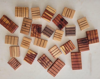 May include: A collection of 20 wooden soap dishes in various shades of brown and red. The dishes are made of cedar wood and have a grooved design to help drain water.