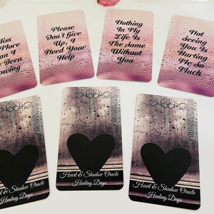 May include: A set of ten oracle cards with a heart and shadow theme. The cards feature a variety of inspirational messages, such as "I miss you more than I have been showing" and "Nothing in my life is the same without you". The cards are designed with a water droplet background and have a black heart shape in the bottom corner.