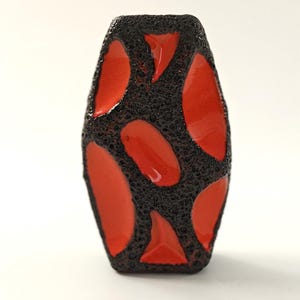 Puede incluir: Un jarrón de cerámica con exterior negro texturizado y vibrantes acentos rojos de forma orgánica. El jarrón tiene un diseño único y llamativo, perfecto para la decoración del hogar. El jarrón mide aproximadamente 15 cm de alto.