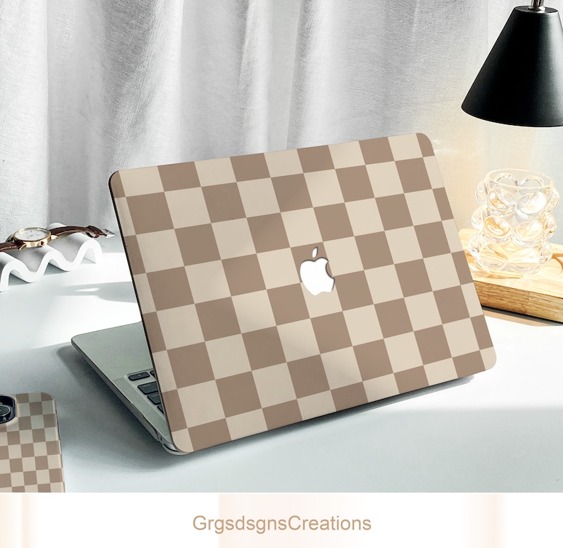 May include: A laptop computer with a brown and beige checkered pattern on the lid. The Apple logo is visible on the lid.