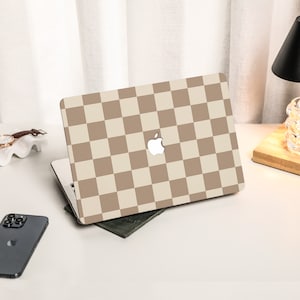 May include: A laptop computer with a beige and brown checkered pattern on the lid. The Apple logo is visible on the lid.