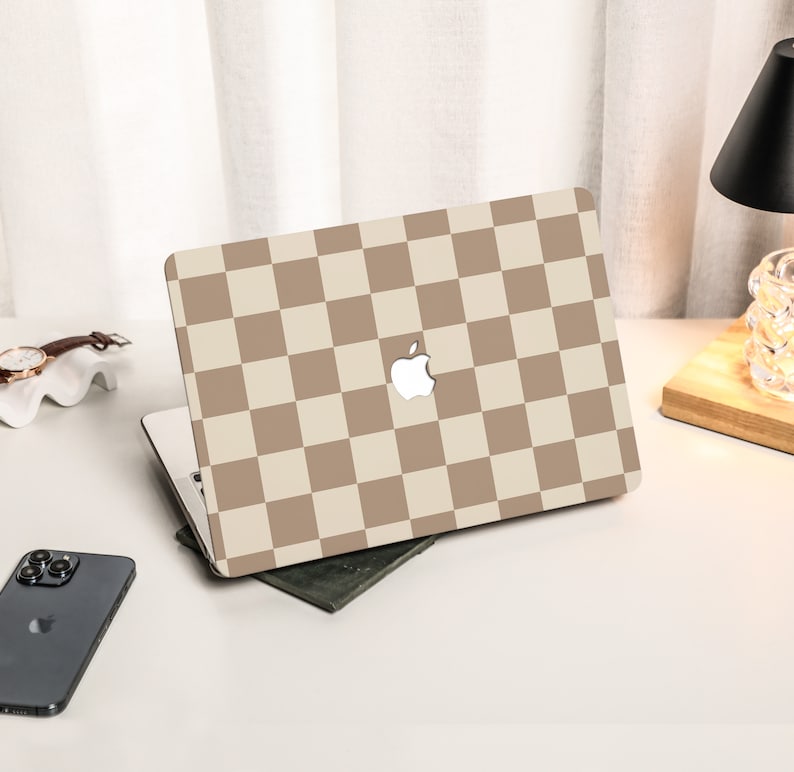 May include: A laptop computer with a beige and brown checkered pattern on the lid. The Apple logo is visible on the lid.