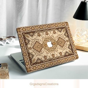 May include: Laptop case featuring a beige, brown, and gold pattern, reminiscent of a traditional rug design. The case is fitted to a laptop, with the Apple logo showing. The design incorporates floral and geometric motifs. The text "GrgsdsgnsCreations" is at the bottom.