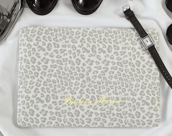 Könnte beinhalten: Eine rechteckige Laptoptasche mit einem hellgrauen und weißen Leopardenmuster. Der Name Paulina Havin ist in einer goldenen Schreibschrift in der Mitte der Tasche eingestickt. Die Tasche ist umgeben von schwarzen Business-Schuhen, einem Flakon Rose of Wilderness Parfüm und einer Armbanduhr mit dunkelbraunem Lederarmband.
