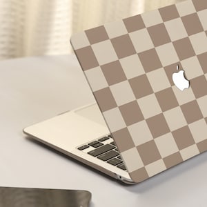 May include: A laptop computer with a brown and white checkered design on the lid. The Apple logo is visible on the lid.