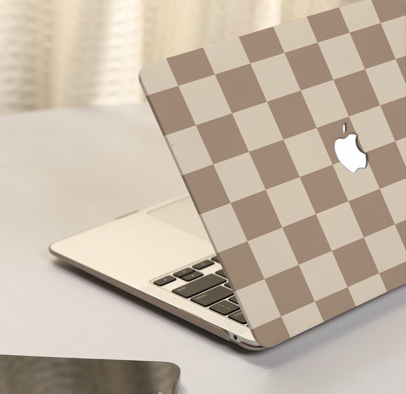 May include: A laptop computer with a brown and white checkered design on the lid. The Apple logo is visible on the lid.