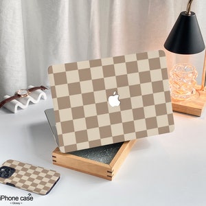 May include: A brown and white checkered laptop skin with an Apple logo. The skin is on a wooden box with a glass top. The text "iPhone case < Glossy >" is on the bottom of the image.