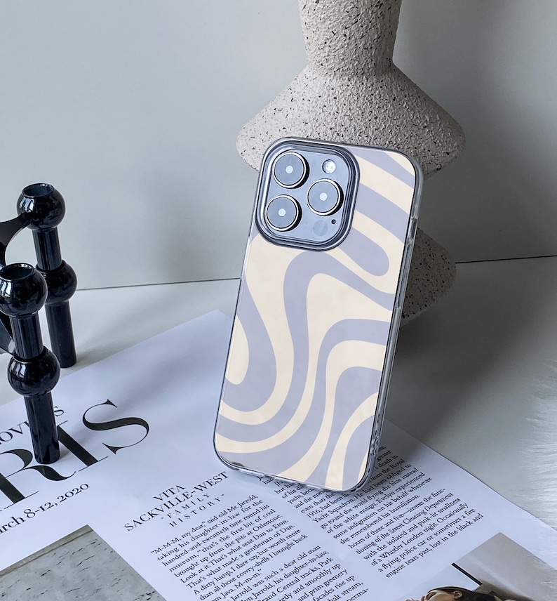 Op de afbeelding: Een transparante telefoonhoes met een abstract swirl-patroon in wit en grijs. De hoes is ontworpen voor een iPhone met een drievoudig camerasysteem.