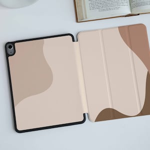 May include: A beige and brown iPad case with a geometric pattern. The case has a flap that folds over the screen to protect it.
