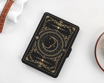 May include: Black leather journal with a gold crescent moon and star design. The cover features intricate floral patterns and a decorative border.