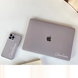 May include: A light purple laptop and a light purple phone case with the name "Carolina" written in white on both items.