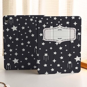 Może przedstawiać: Czarne etui na iPada z białym wzorem gwiazd i ozdobną ramką z tekstem "The Stars Are Aligned".