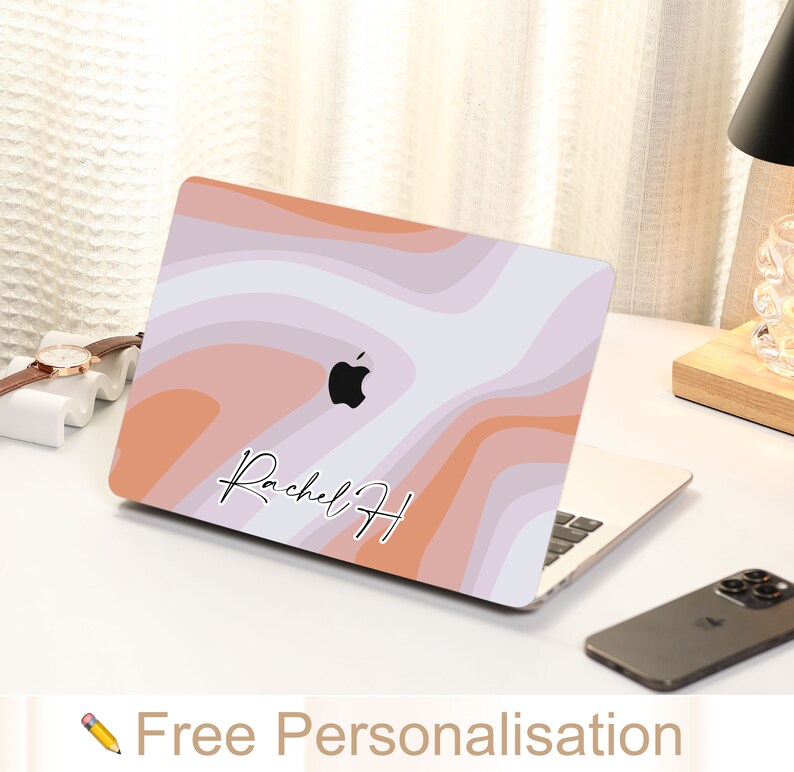 May include: A laptop skin with a pink, orange, and white abstract design. The skin features the text "Rachel H" in a handwritten font. The skin is designed to fit a laptop computer.