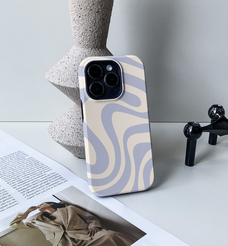 Op de afbeelding: Een telefoonhoesje met een wervelend abstract patroon in tinten lichtblauw en beige. De hoes is ontworpen voor een telefoon met een camerabult.