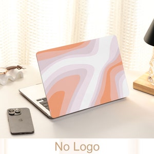 May include: A laptop computer with a pink and orange abstract design on the lid. The laptop is closed and sitting on a white surface.