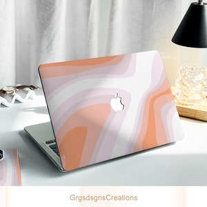 May include: A pink and orange laptop skin with a swirling abstract pattern. The skin has a white Apple logo in the center.