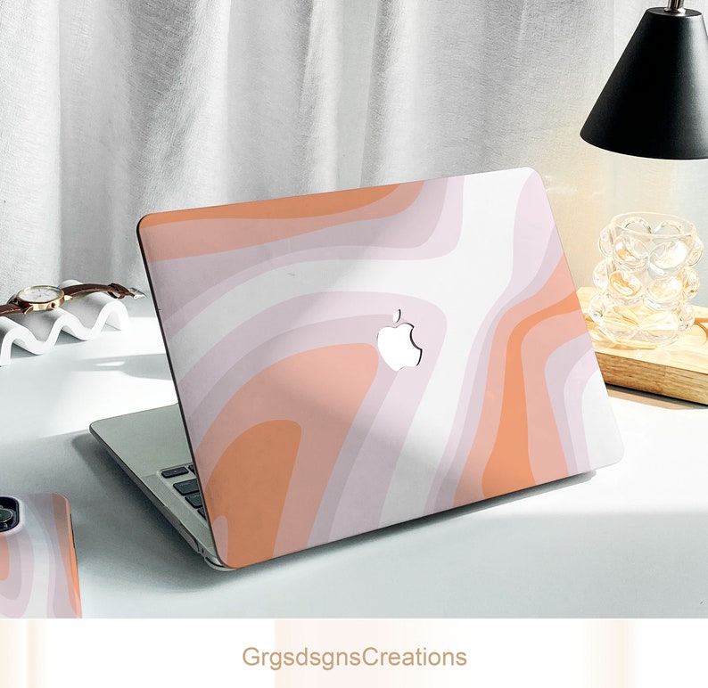 May include: A pink and orange laptop skin with a swirling abstract pattern. The skin has a white Apple logo in the center.