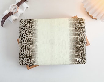 May include: A cream-colored laptop case with a crocodile skin pattern. The case has a central cream panel with a darker, textured border. The word "Iris" is printed on the lower right corner. A brown leather watch and a white decorative stand are in the background.