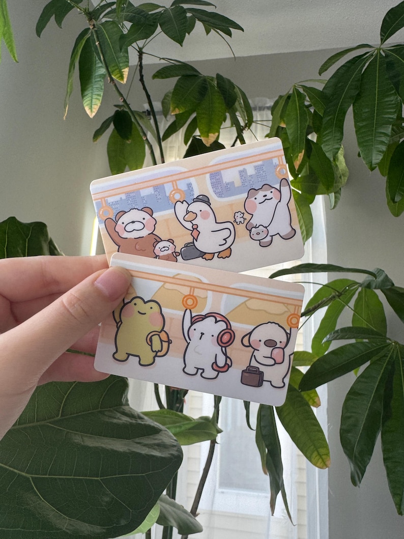 May include: A white ceramic mug with a black handle and the text "But First, Coffee" in a bold, black font. The mug is set against a blurred background, suggesting a cozy setting.