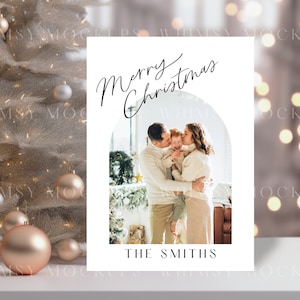 May include: A white Christmas card with a photo of a family of three. The parents are kissing their child on the cheek. The card has the text "Merry Christmas" and "The Smiths" printed on it.