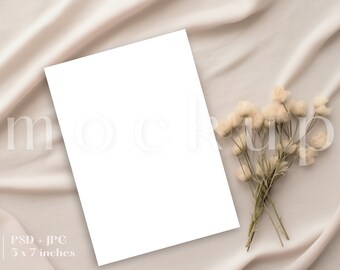 May include: A white card mockup on a beige fabric background with a bouquet of dried white flowers. The card is 5 x 7 inches.