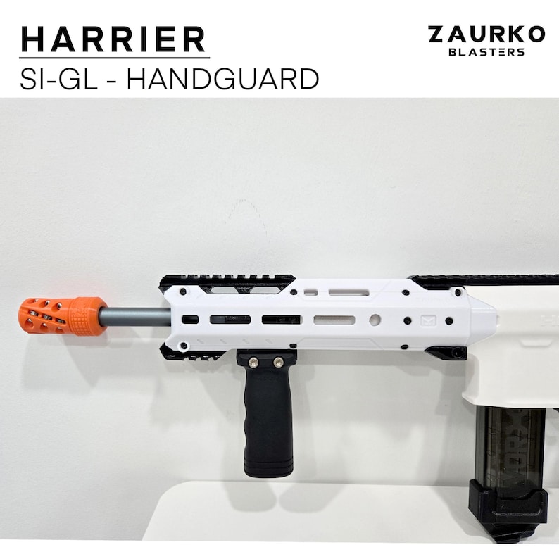 Puede incluir: Un guardamanos Harrier SI-GL blanco y negro con un freno de boca naranja. El guardamanos est&aacute; unido a un blaster blanco con una empu&ntilde;adura vertical negra. El texto "Zaurko Blasters" es visible en la esquina superior derecha de la imagen.