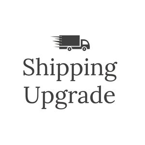 May include: A black and white graphic of a delivery truck with motion lines above the text "Shipping Upgrade" in a serif font. The image is on a white background.