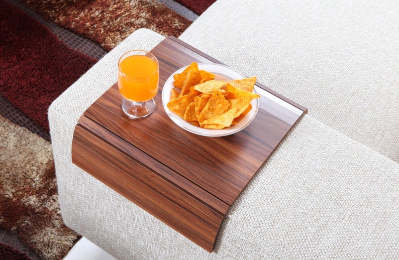 K&ouml;nnte beinhalten: Ein Holztablett mit abgerundeter Kante steht auf einem wei&szlig;en Sofa. Auf dem Tablett befinden sich ein Glas Orangensaft und eine wei&szlig;e Sch&uuml;ssel gef&uuml;llt mit Tortilla-Chips.