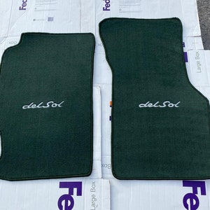 May include: Two dark green car floor mats with the text "del Sol" embroidered in white.