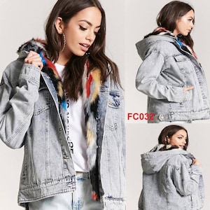 May include: A light-wash denim jacket with a faux fur-lined hood and collar. The fur trim features a mix of colors, including red, yellow, and blue. The jacket has a button-up front, pockets, and a classic denim design.