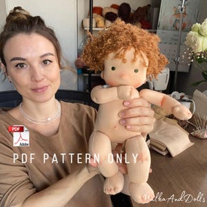 May include: A handmade doll with a soft, beige body, red curly hair, and freckles. The doll is being held by a person. The text "PDF PATTERN ONLY" is visible in the image.
