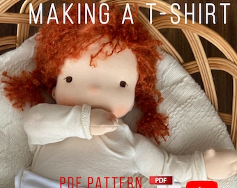 May include: A handmade doll with red hair wearing a white t-shirt and diaper. The image includes text that reads "MAKING A T-SHIRT", "PDF PATTERN", and "VIDEO INSTRUCTION". The doll is designed for a 16-inch baby doll.