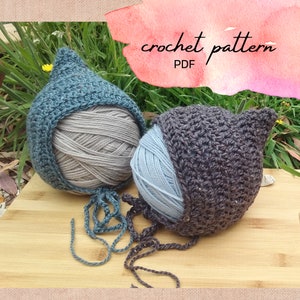 May include: Two crochet yarn cozies, one teal and one brown, each covering a ball of yarn. The yarn is gray and light blue. The text "crochet pattern PDF" is written in cursive on a watercolor background.