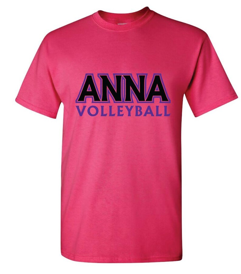 K&ouml;nnte beinhalten: Pinkes T-Shirt mit schwarzem Text, der "ANNA VOLLEYBALL" in einer fetten, umrandeten Schrift mit violetten Akzenten sagt.